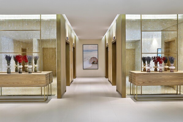 A hallway with mirrored walls, a central artwork, and two wooden tables with vases. - Avani Ibn Battuta Dubai Hotel (Dubai)