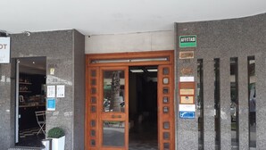 A building entrance with a wooden door, a signboard, and a trash bin. - Aquae Romanae Piazza Lauro (Sorrento)
