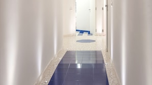 A narrow hallway with a blue-tiled floor and white walls. - Aquae Romanae Piazza Lauro (Sorrento)