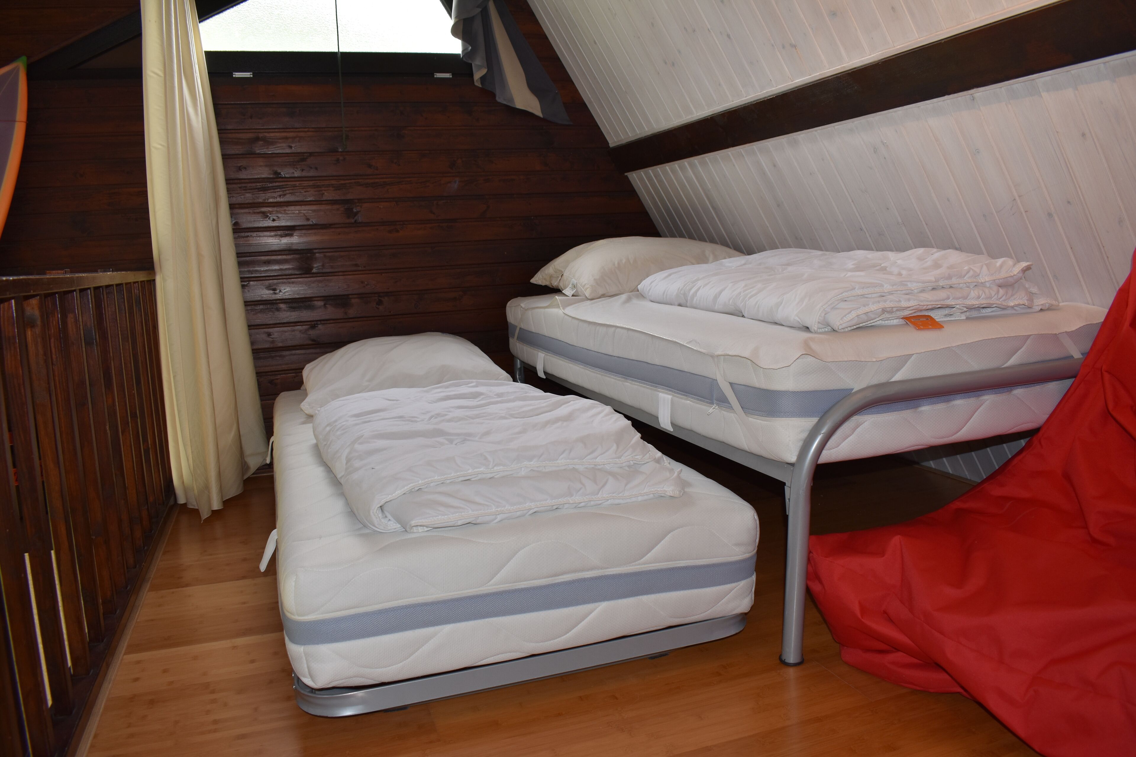 Una habitación con dos literas, paredes de madera y una ventana con cortinas.