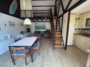 A loft-style living space with a dining area, a staircase, and a kitchen.