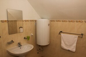 A bathroom with a sink, mirror, towel rack, and a water heater.