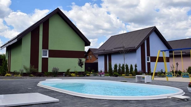 A swimming pool area with a building in the background. - Perlyna Dzvinkova (Dzvinkove)