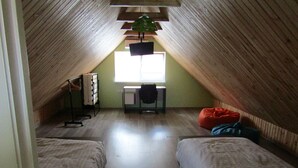 A small, sloped-roofed attic bedroom with two beds, a desk, and a window. - Perlyna Dzvinkova (Dzvinkove)