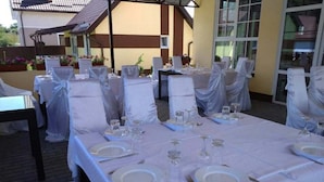 An outdoor dining area with tables set for a meal, covered with white tablecloths and chairs draped in white fabric. - Perlyna Dzvinkova (Dzvinkove)