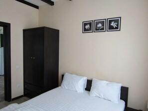 A bedroom with a bed, a wardrobe, and three framed pictures on the wall.