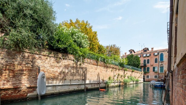 A canal with a brick wall on one side and a row of buildings on the other.