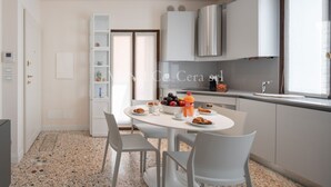A modern kitchen with white cabinets, a granite countertop, and a dining area with a round table and chairs.