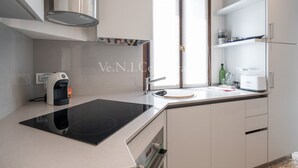 A modern kitchen with a black induction cooktop, a built-in oven, a coffee machine, and a sink.