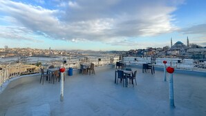A rooftop terrace with tables and chairs, overlooking a cityscape with a prominent mosque. - Biter Hotel (Istanbul)