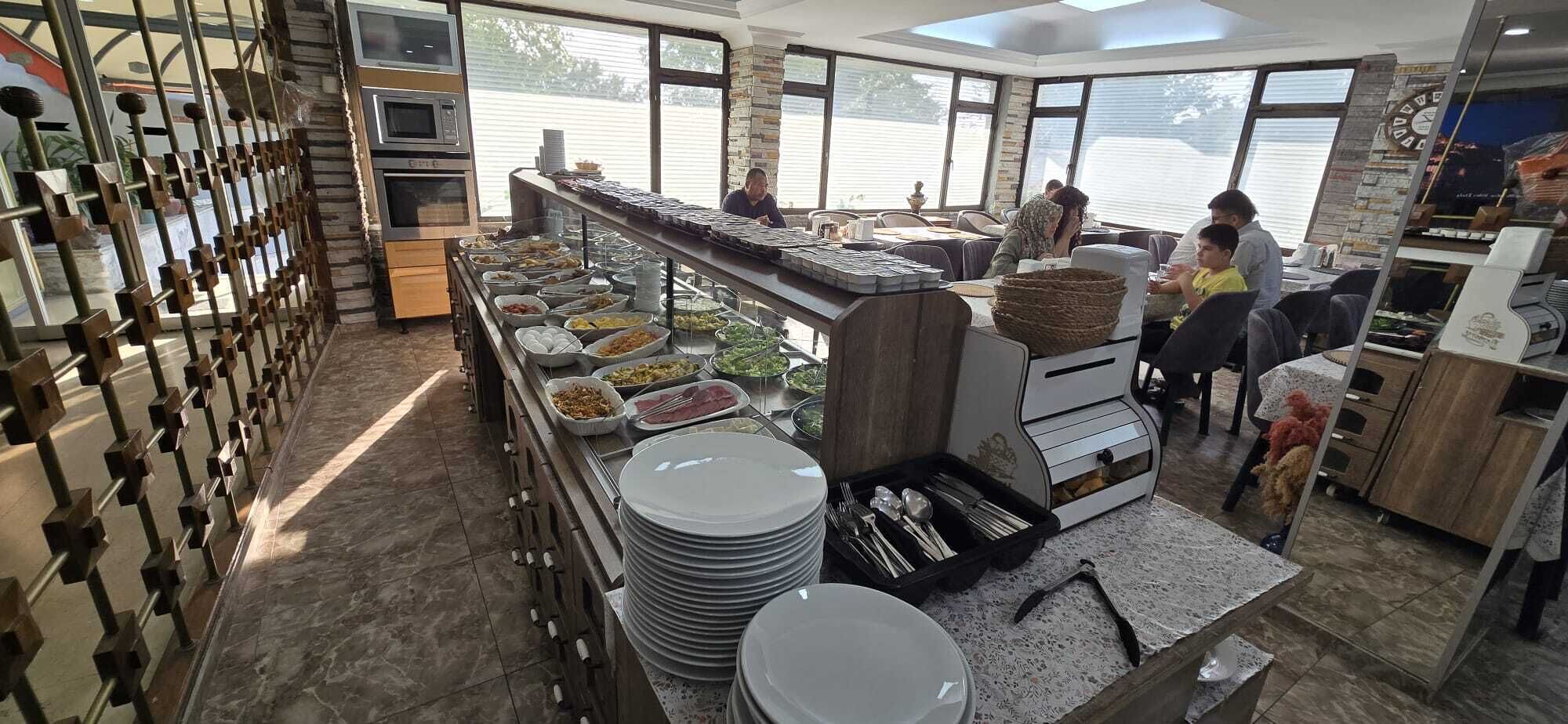 A buffet setup with various food items, a coffee machine, and a seating area with tables and chairs.