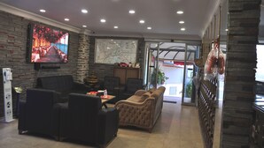 A hotel lobby with seating, a TV, a map, and a view of the sea. - Biter Hotel (Istanbul)