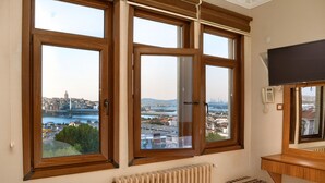 A room with three large windows offering a city view, a built-in telephone, and a radiator. - Biter Hotel (Istanbul)