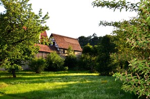A traditional half-timbered house surrounded by lush greenery. - Holiday suite "Belle Etage" in the "Ferienhaus Burgcafé" (Betzenstein)