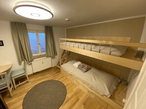 Une chambre avec un lit superposé, une fenêtre, un bureau et une chaise.