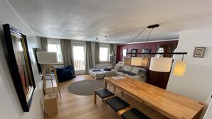 En moderne stue med et træspisebord, bænke, en sofa og et stort spejl.