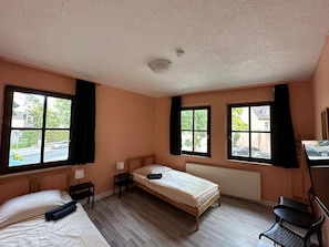 Una habitación con dos camas, un escritorio y una silla.
