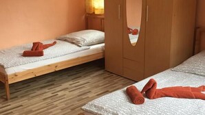 Une chambre avec deux lits simples, un plancher en bois et une armoire avec un miroir.
