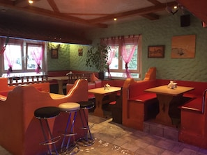 Un interior de restaurante con cabinas, mesas altas y taburetes de bar.