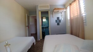 Une chambre d’hôtel avec deux lits, une salle de bain et un petit coin salon.