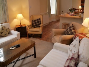 A living room with a sofa, armchairs, a coffee table, and a dining area with a table and chairs. - Bogroy - a cottage that sleeps 6 guests in 3 bedrooms (Aberlour)