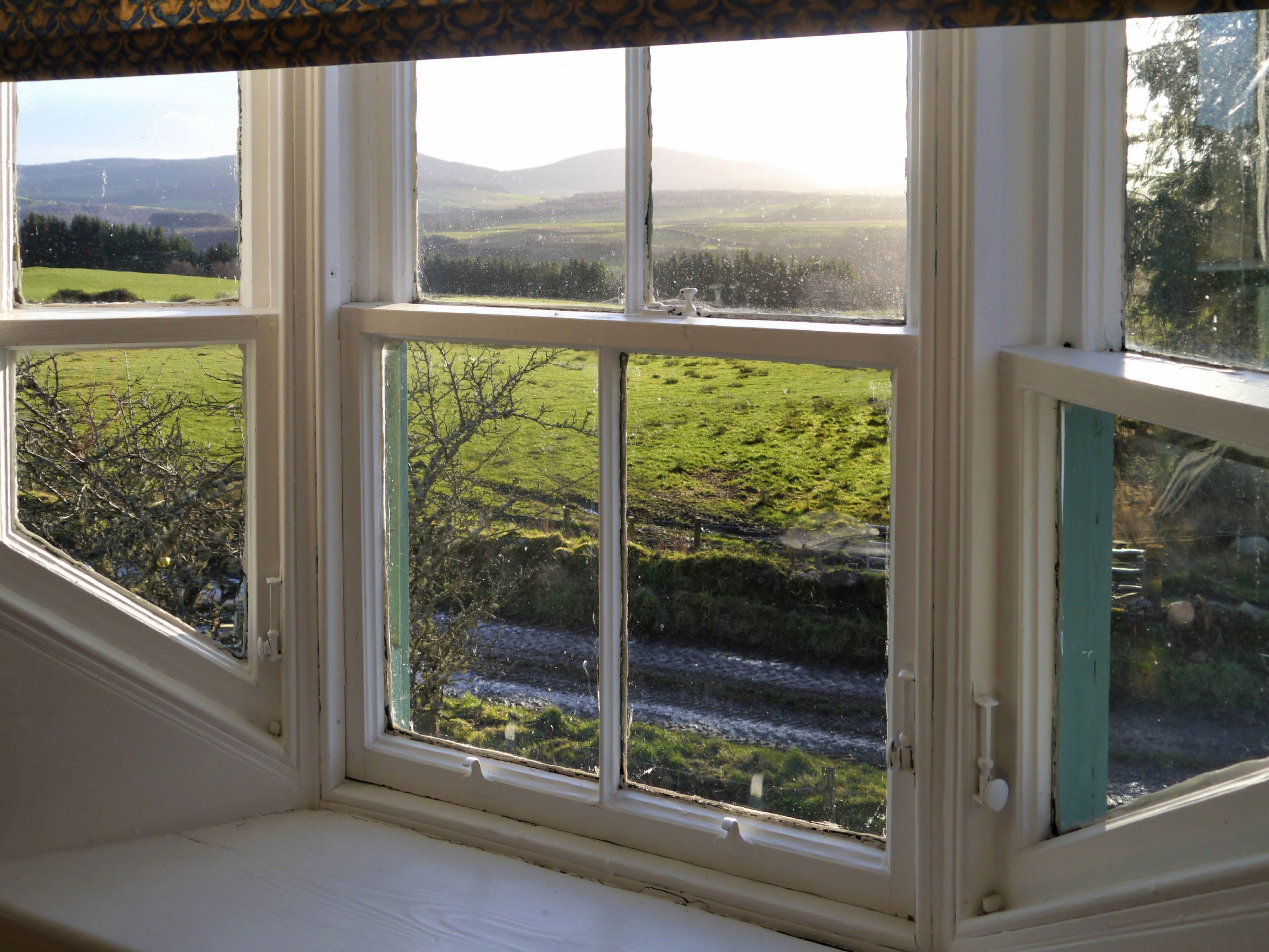 A room with a large window overlooking a rural landscape.