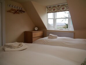 A bedroom with a bed, a dresser, a window with a view, and a radiator.