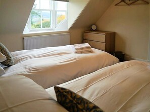 Un dormitorio con dos camas, una ventana, un radiador y un aparador de madera.