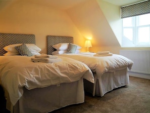 Een hotelkamer met twee bedden, een raam en een radiator.