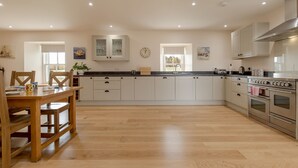 A spacious kitchen with wooden flooring, white cabinets, and stainless steel appliances.