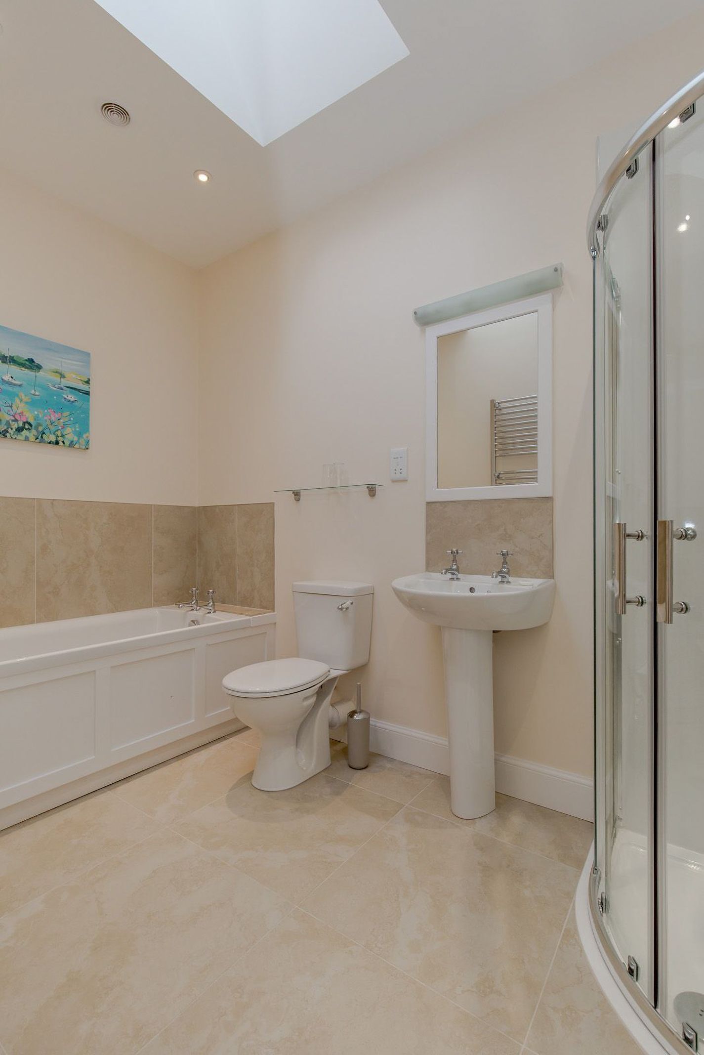 Une salle de bain moderne équipée d’une baignoire, de toilettes, d’un lavabo et d’une douche à parois en verre.