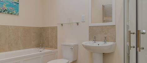 Une salle de bain moderne équipée d’une baignoire, de toilettes, d’un lavabo et d’une douche à parois en verre.