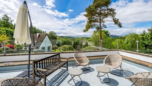 Een terras met rieten stoelen, een bank en een witte parasol.