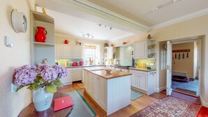 Una cocina amplia con muebles blancos, una isla central y vista al área de comedor.