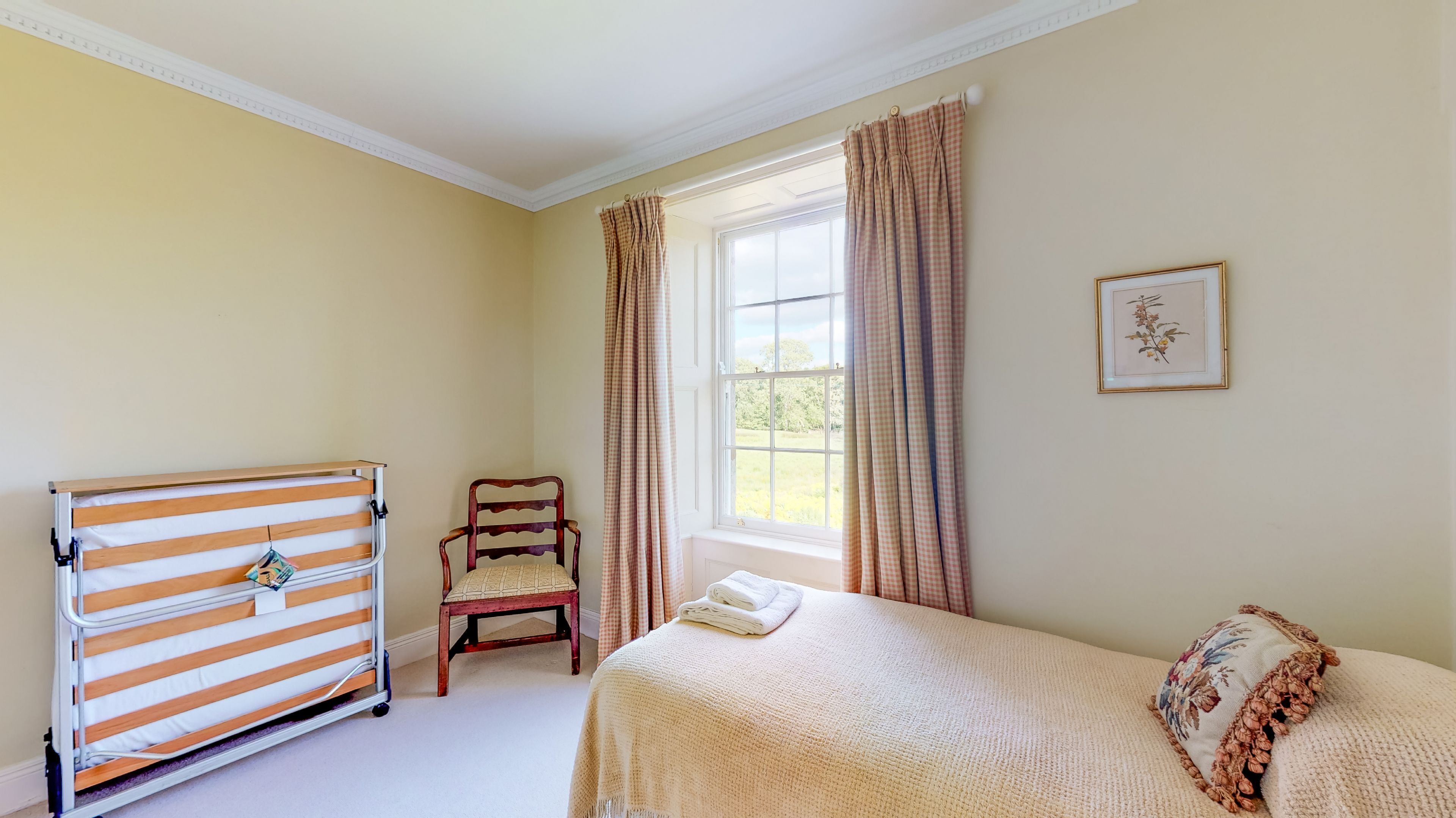 A bedroom with a bed, a chair, a radiator, and a window with curtains.
