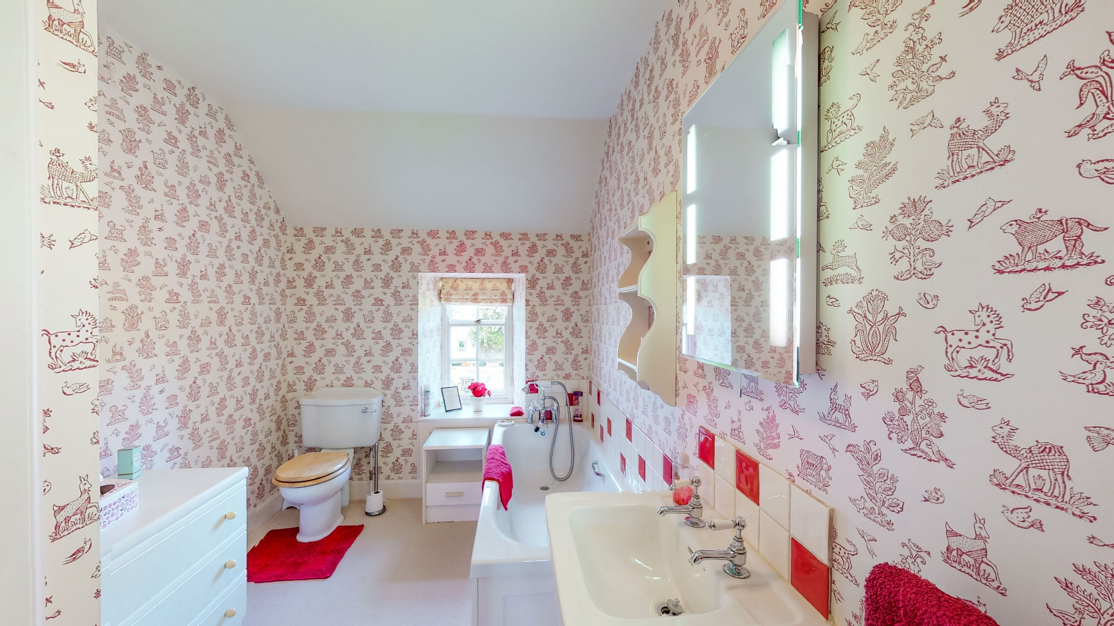 A bathroom with patterned wallpaper, a toilet, sink, and mirror.