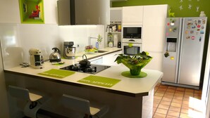 Una cucina moderna con un'isola centrale, un piano cottura a gas, un bollitore e un frigorifero.