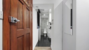 Een gang die leidt naar een badkamer met toilet en douche.
