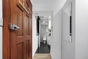 A hallway leading to a bathroom with a toilet and a shower.
