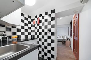 A modern kitchen with black and white checkered tiles, a stainless steel sink, and a red fire extinguisher.