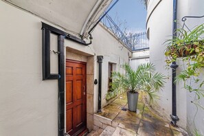 A narrow alleyway with a wooden door, a potted plant, and a metal fence. - Westbourne Ter Rd W2, Paddington, Warwick Ave (Greater London)