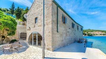 A stone building with a balcony overlooking a body of water.