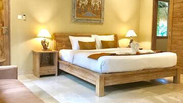 Une chambre avec un lit en bois, deux tables de chevet avec des lampes, un grand tableau au mur et une fenêtre donnant sur un paysage verdoyant.