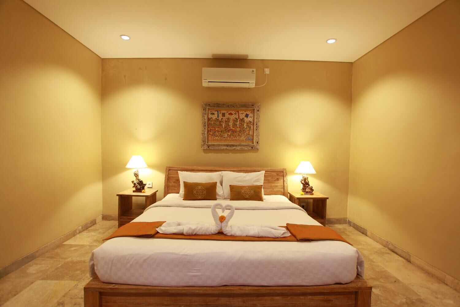 Ein Hotelzimmer mit einem großen Bett, zwei Nachttischlampen, einer Wand-Klimaanlage und einem Wandteppich.
