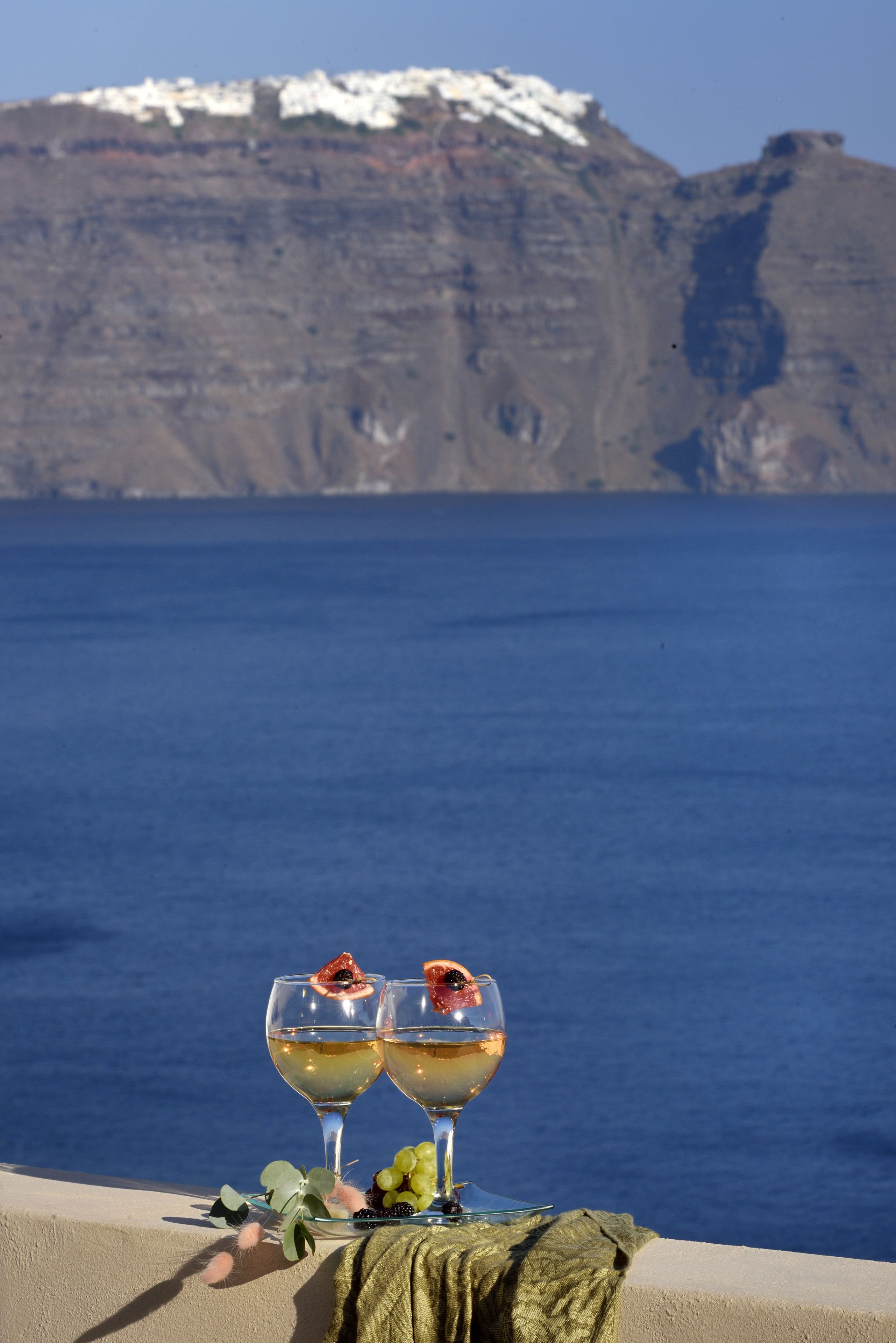 Two glasses of wine with a view of a mountainous coastline.