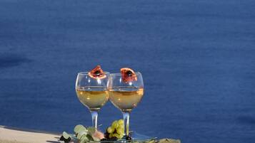 Two glasses of wine with a view of a mountainous coastline.