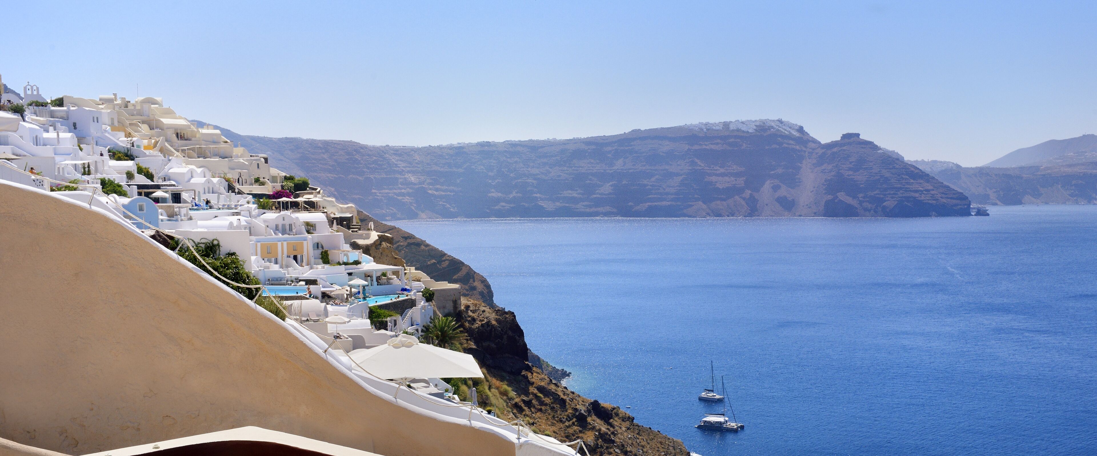 A coastal village with white buildings, a clear blue sea, and boats.