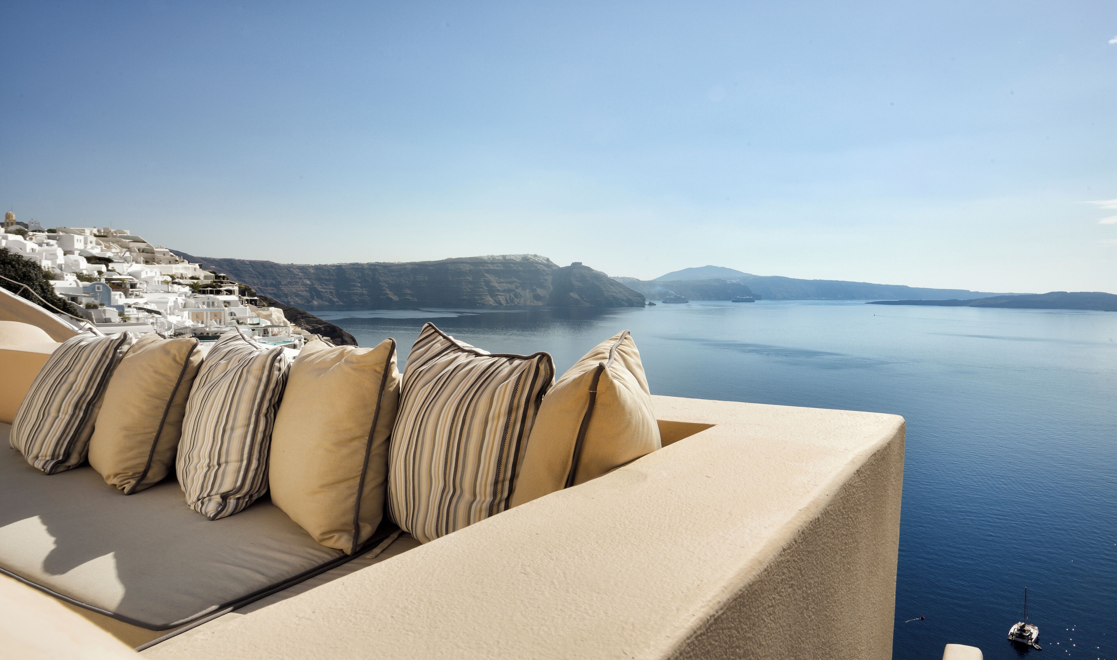 Un balcon donnant sur la mer, avec vue sur une mer calme et des bâtiments blancs.
