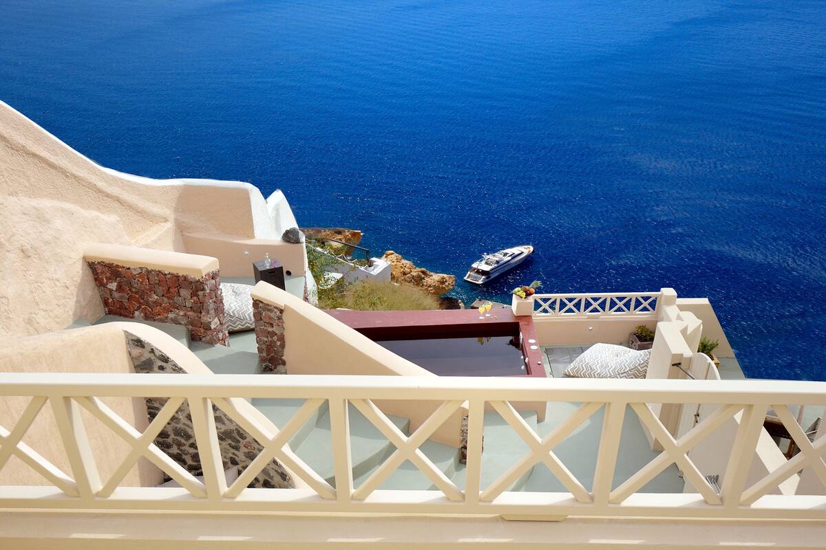 A balcony with two wooden lounge chairs and a view of the sea.