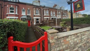 A row of red brick houses with a red gate and a sign for 'Blenheim Guest House'. - Blenheim Guest House York (York)
